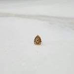 Close-up of Peacock Plume gold nose pin placed on a flat surface, showcasing detailed feather-inspired design