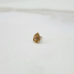 Peacock Plume gold nose pin placed on a white surface, highlighting feather-inspired detailing and elegant craftsmanship
