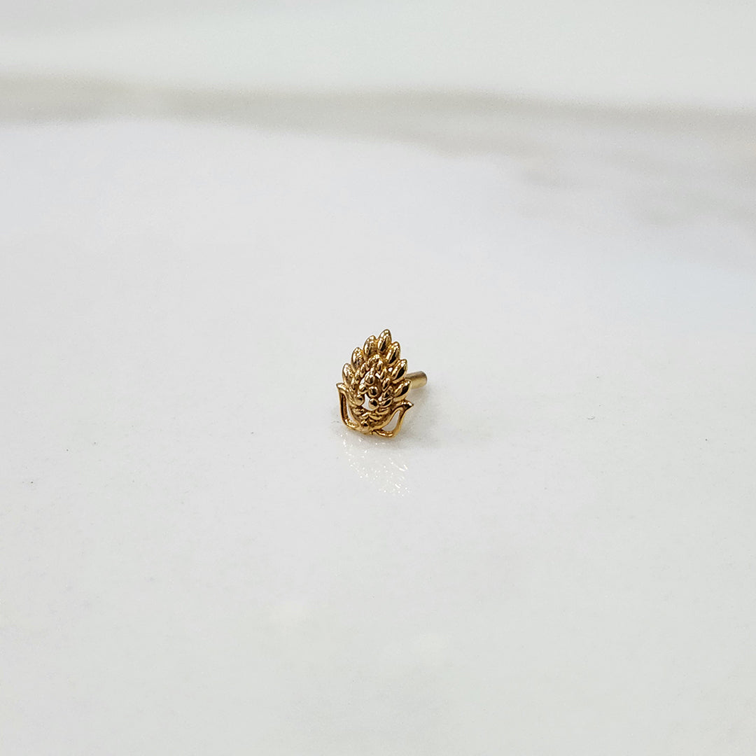 Peacock Plume gold nose pin placed on a white surface, highlighting feather-inspired detailing and elegant craftsmanship