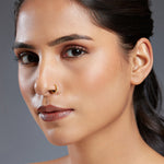 Model wearing Regalia Aura gold nose ring with ruby and white stones, showcasing a luxurious and elegant look