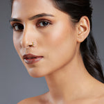 Model wearing Regalia Aura gold nose ring in 18K gold with black and white stones, perfect for traditional outfits