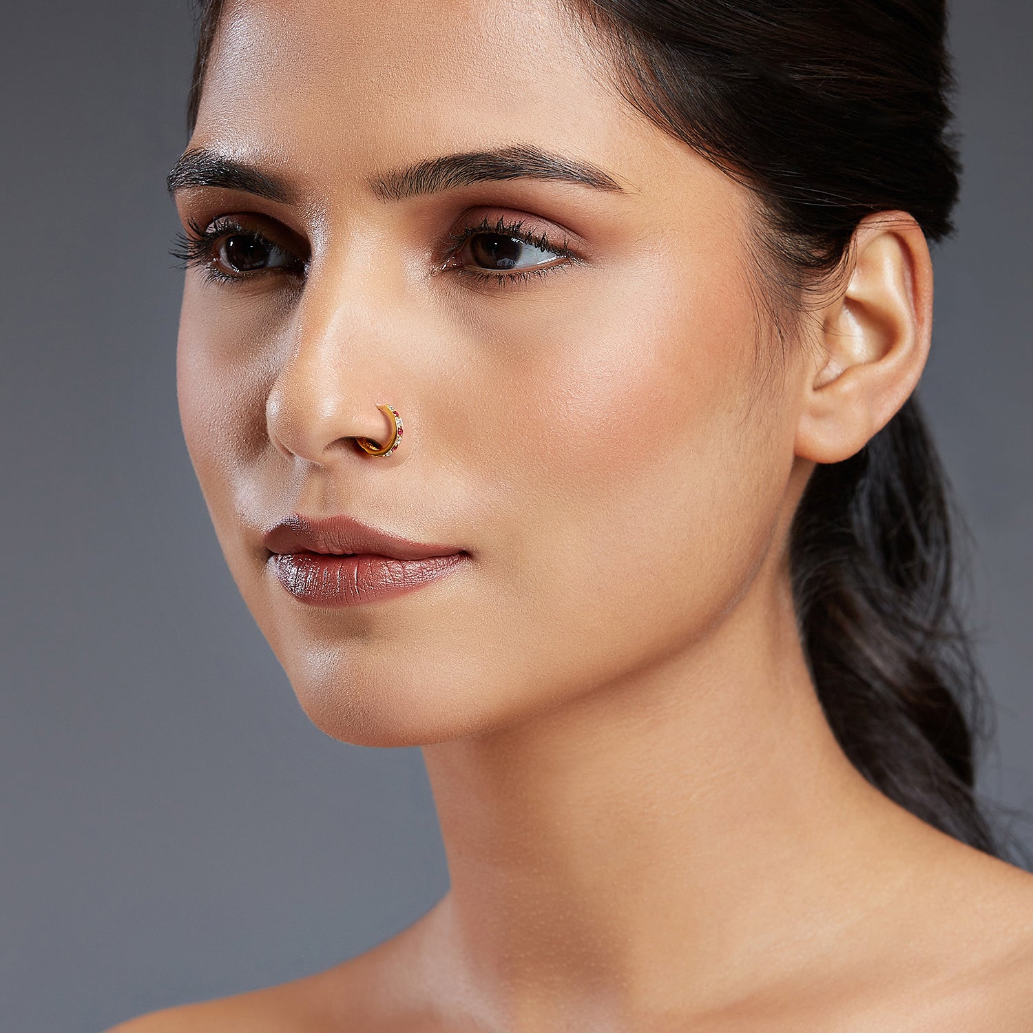 Model wearing Regalia Aura Gold Nose Ring in 18K gold with alternating white and pink stones for a royal and elegant look