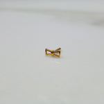 Ribbon Whisper gold nose pin with delicate bow-tie inspired design placed on a flat surface in close-up view