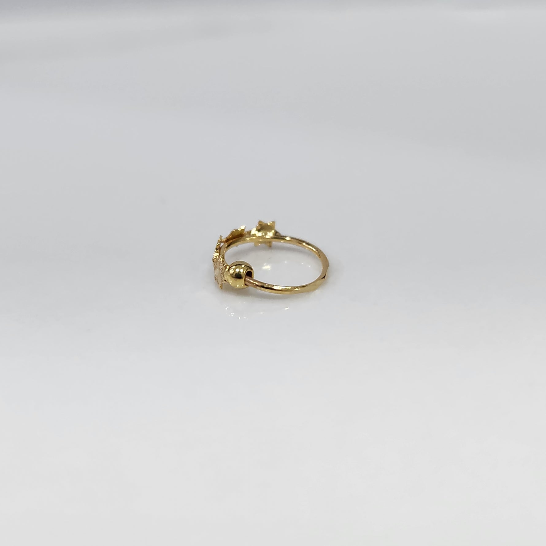 Stars Prism gold nose ring in 18K gold featuring star-shaped design, shown in angled studio view on plain background