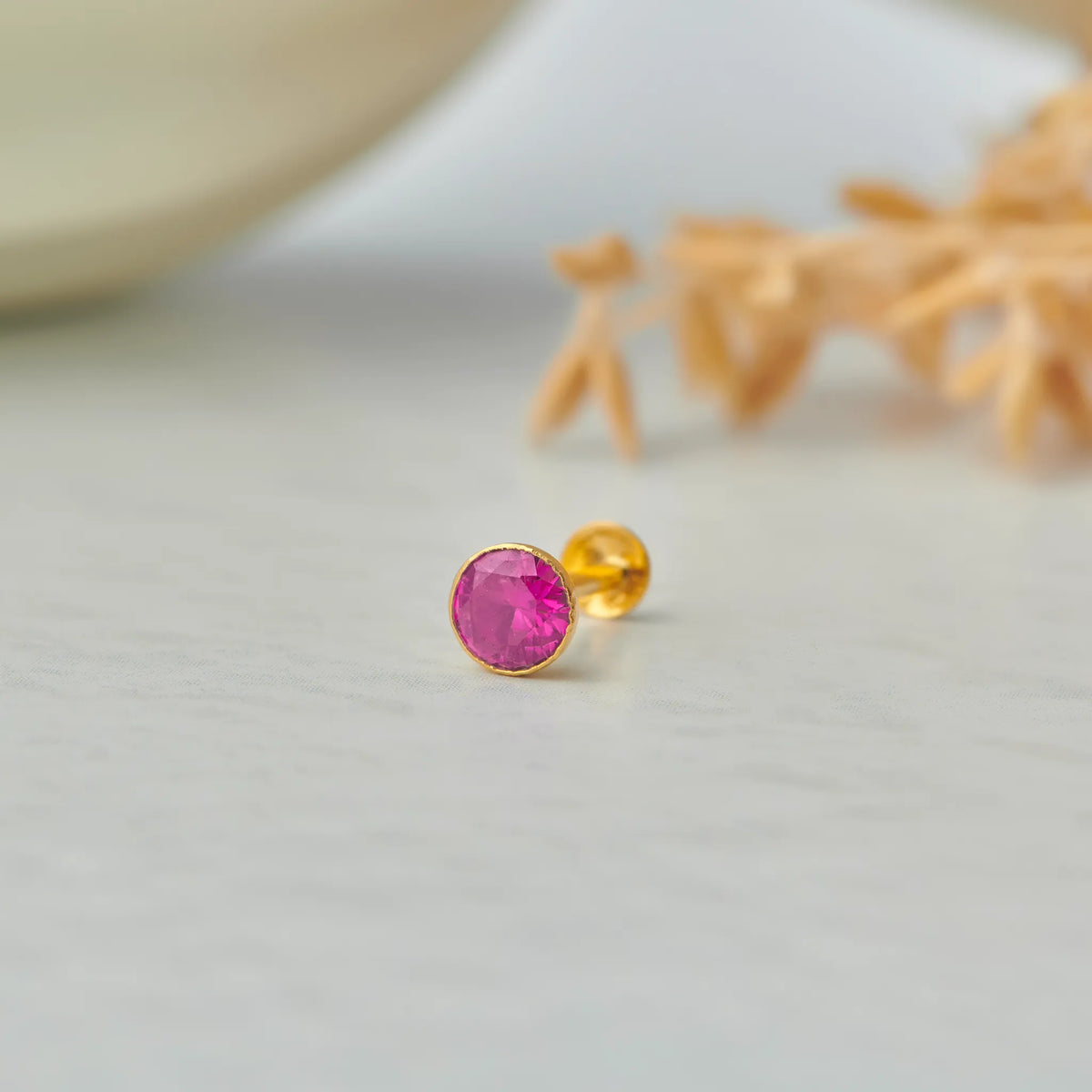 Gold stone nose pin with pink gemstone front view on white background
