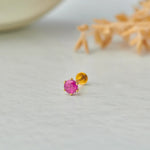 Close up of single ruby stone gold nose pin on white background