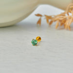 Close up of emerald green stone gold nose pin on neutral background