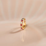Close up of gemstone studded gold nose ring placed on a soft peach toned surface with elegant radial background